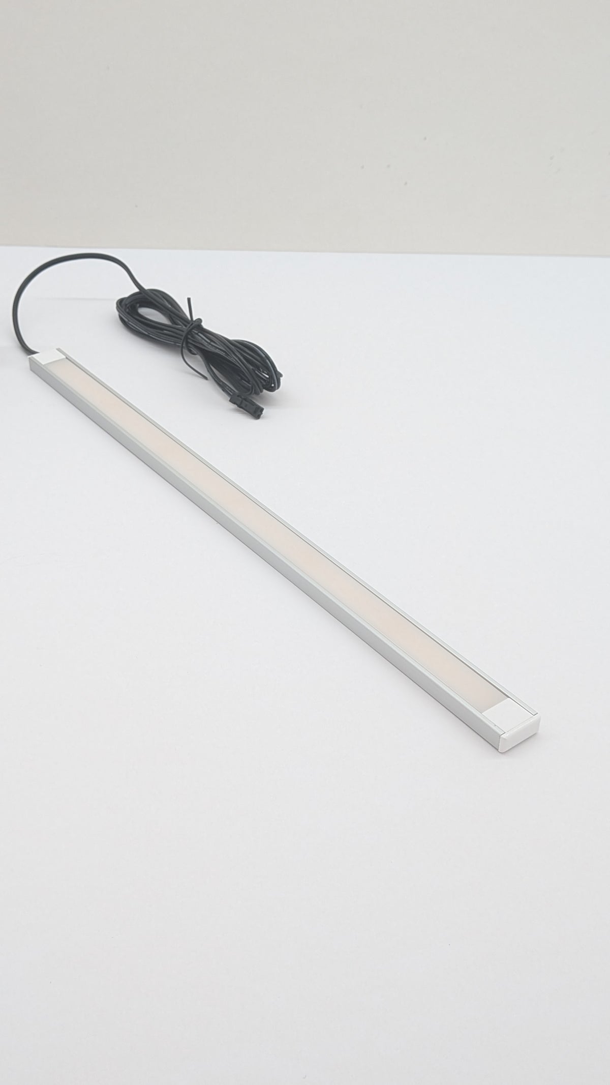 Natural white dotless LED strip lighting up a display cabinet shelf