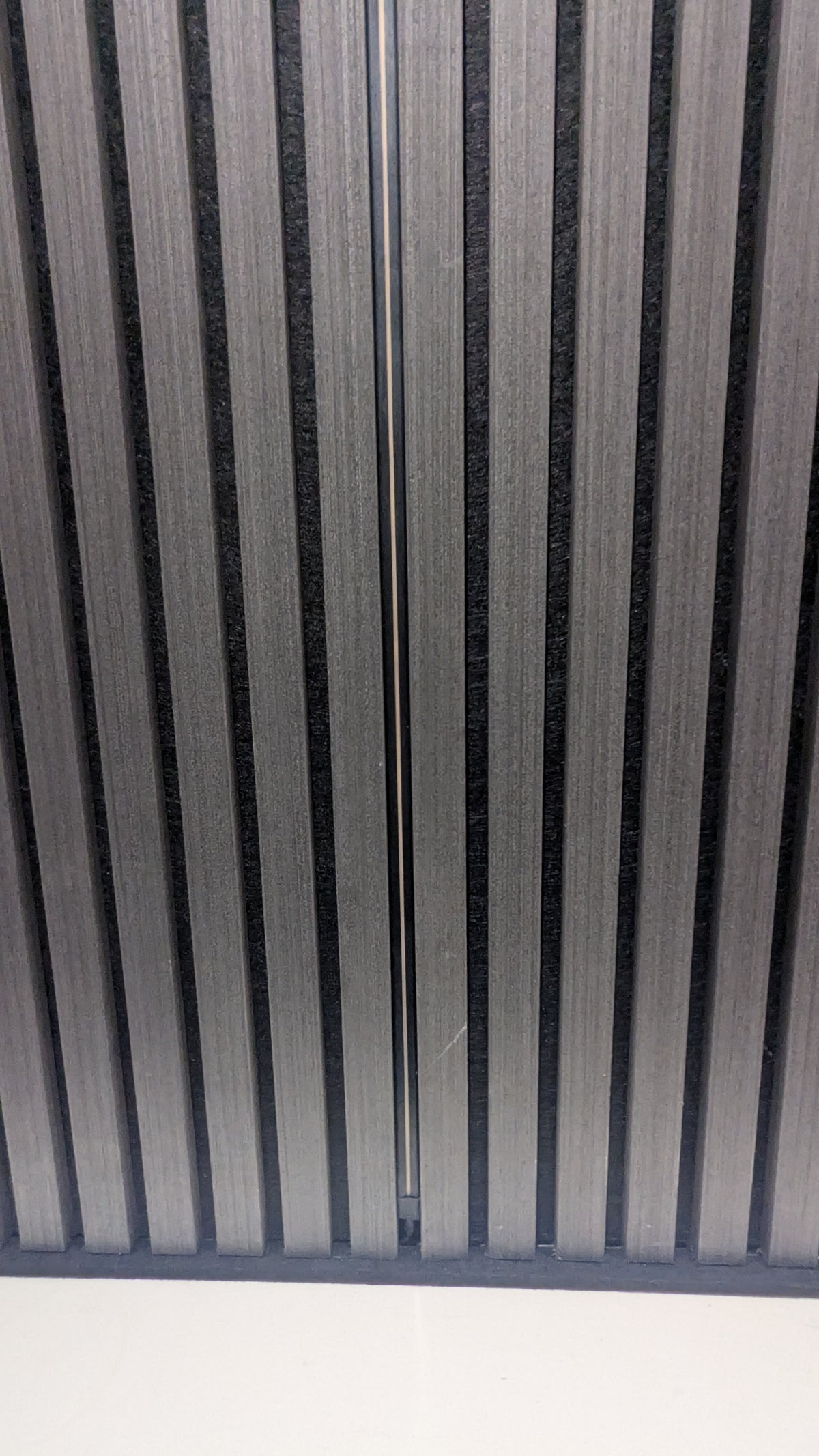 Daylight 4000K LED strip lighting up a slatted acoustic wall in a living room