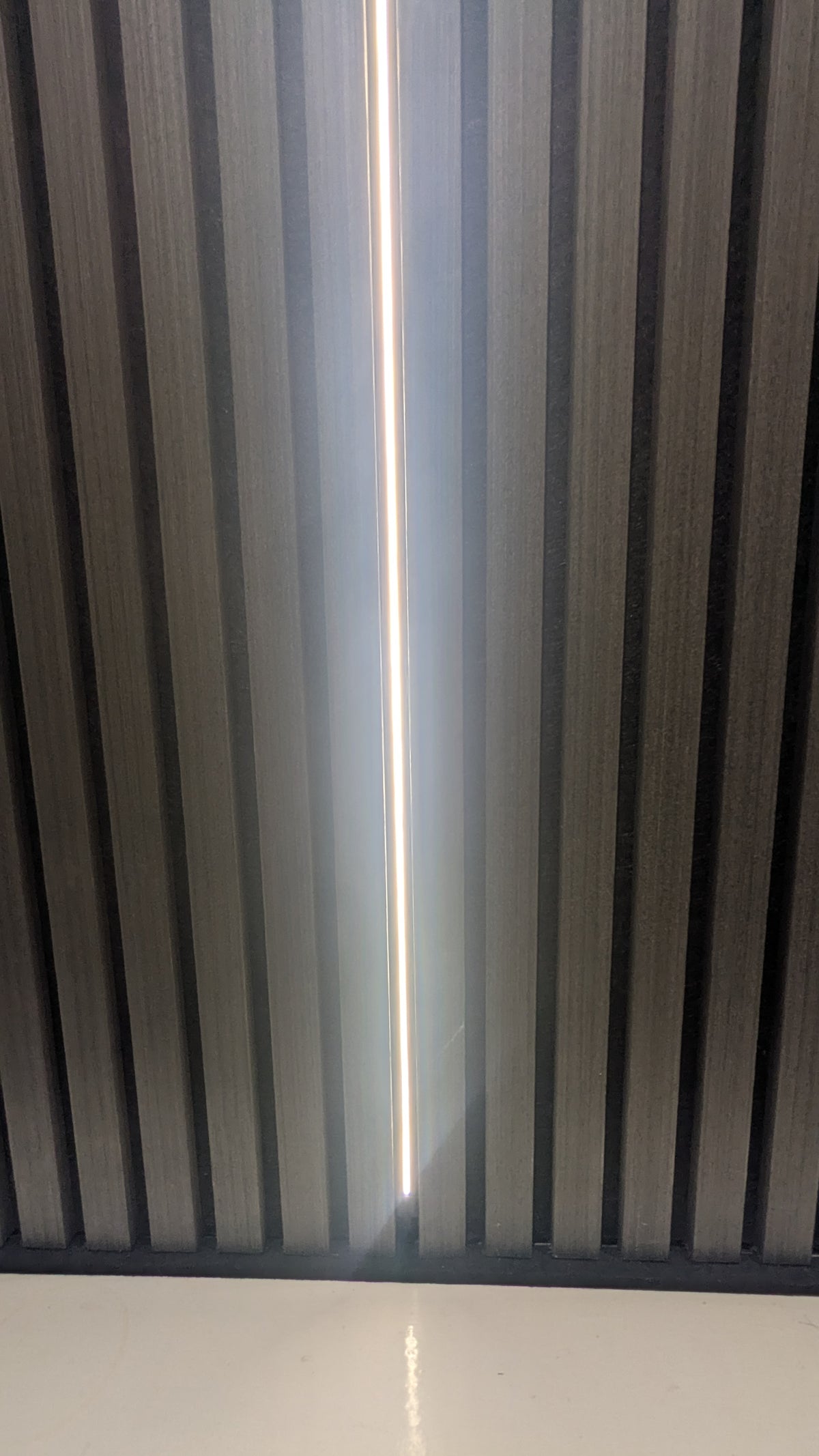 Slim LED strip hidden in acoustic slat panelling, shown in warm white 3000K